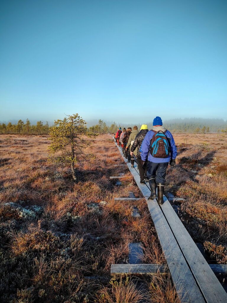 Retkeilijöitä nevan ylittävillä pitkospuilla