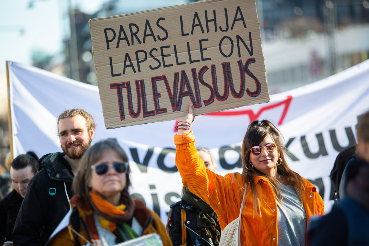 Mielenosoittaja pitää päänsä päällä kylttiä, jossa lukee paras lahja lapselle on tulevaisuus.