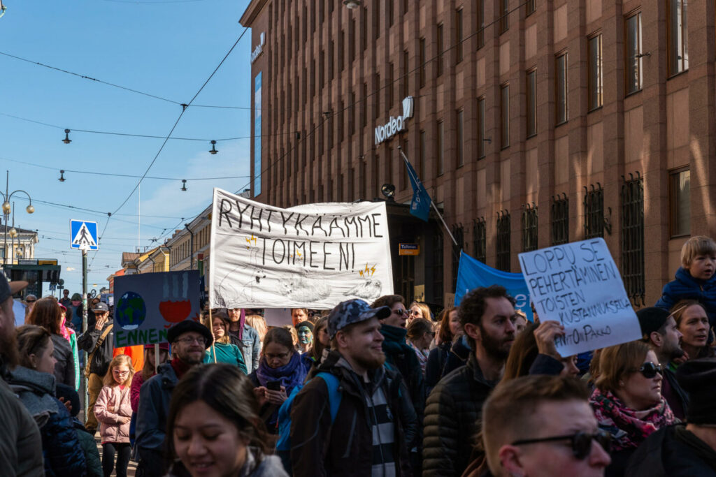 Kuvassa on mielenosoittajia kulkemassa kaupungin kadulla.