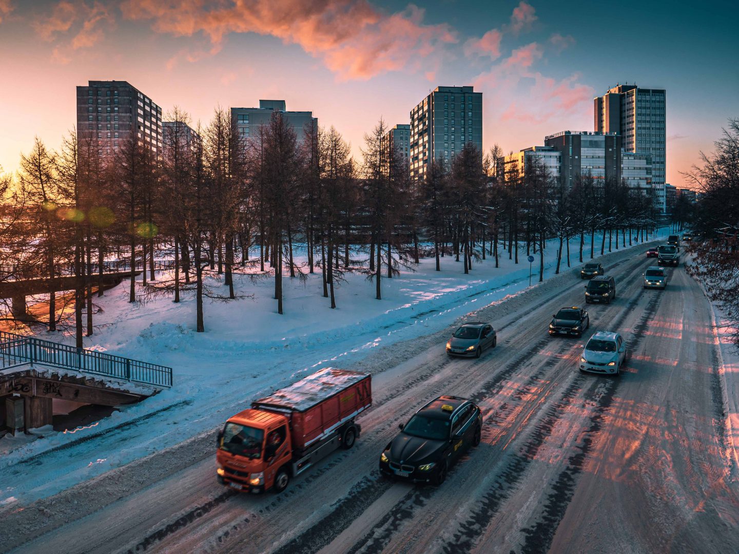 Kuvassa on autoja tiellä. Taustalla näkyy puita ja taloja.