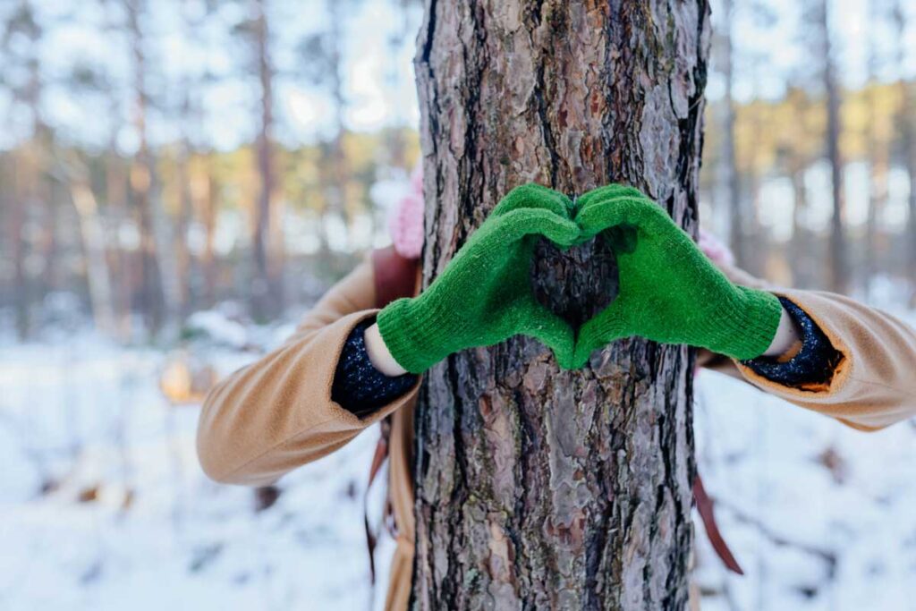 Sormet muodostavat sydämen puun edessä.