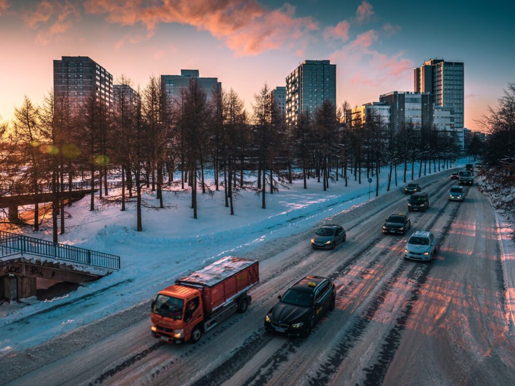 Autoliikennettä talvella ja taustalla kerrostaloja ja auringonlasku.